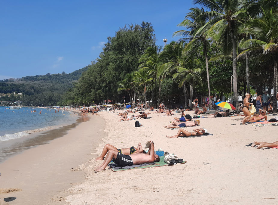 туристы загорают на песке у воды на Камале